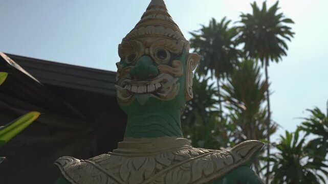 Close up tilt down shot of a green temple guardian statue at Wat Khon Tai on Don Khon in Si Phan Don, Laos.