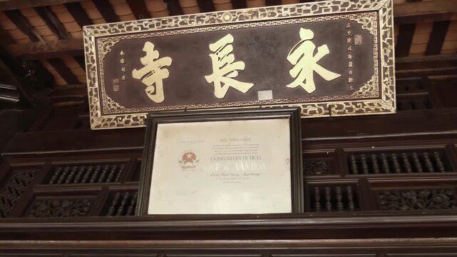 Interior of the famous Vinh Trang Pagoda in Mekong Delta, Vietnam with wooden elements and big tablet with gilded Chinese characters and traditional Chinese patterns