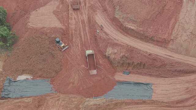 A crawler bulldozer is leveling the fill soil unloaded from a truck for road construction