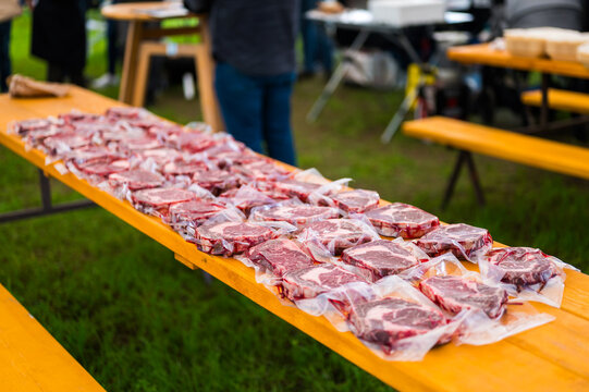 Rows of raw, marbled ribeye steaks laid out on butcher paper during a Steak Cookoff Association (SCA) BBQ competition, showcasing premium meat quality and preparation for professional grilling.