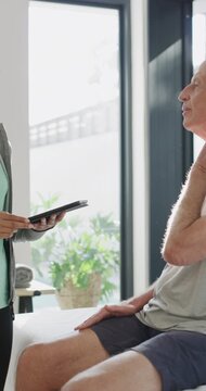 Physiotherapist, tablet and old man in clinic with neck pain, osteoporosis or patient wellness survey. Senior person, healthcare worker and talk in consultation with tech, injury and physiotherapy