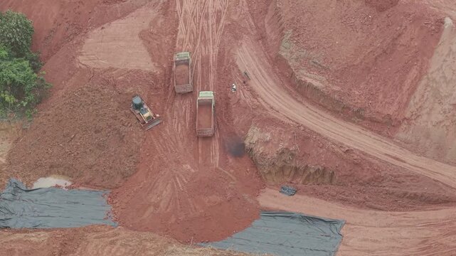 A crawler bulldozer is leveling the fill soil unloaded from a truck for road construction