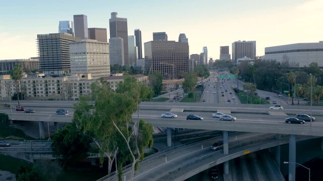 Aerial view of downtown Los Angeles freeway traffic at dusk featuring skyscrapers and multi level highway interchange.