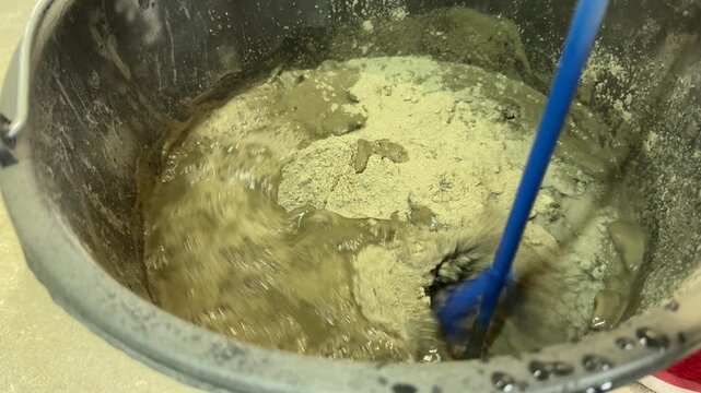 Mixing liquid cement for construction, Close-up of liquid cement being mixed in a large container