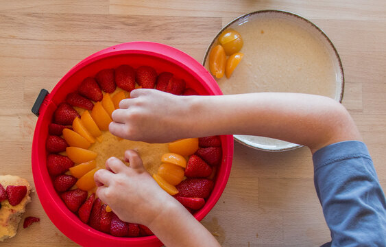 Children decorating a homemade cake with berries, close-up