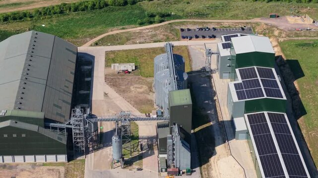 Aerial view of Navara Oat Milling industrial plant with silos, solar panels, and warehouses surrounded by green fields Kettering, England, United Kingdom.