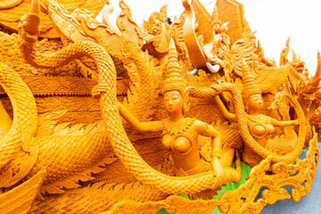 Obraz premium Stunning yellow wax sculpture featuring beautiful mythical female figures holding a Naga tail during a candle parade.