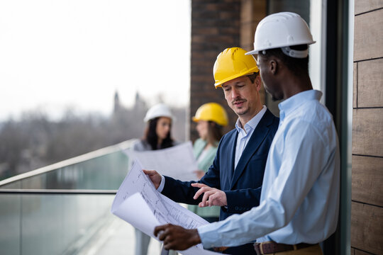Diverse construction team discussing blueprints on job site