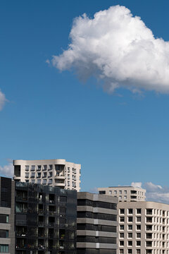 Clouds dominate the blue sky above Lyon buildings in La Confluence, where residential architecture and facade shapes mark an urban edge in France