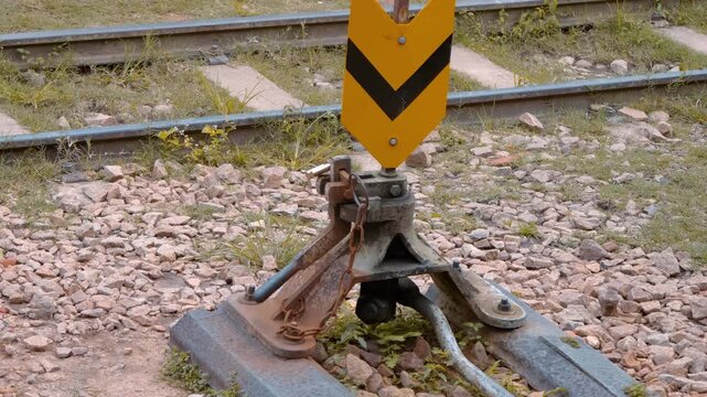 An old railroad switch stand, also known as a turnout or points lever, used to manually change the direction of train tracks with a lever and a target (the orange sign) that indicates the track 