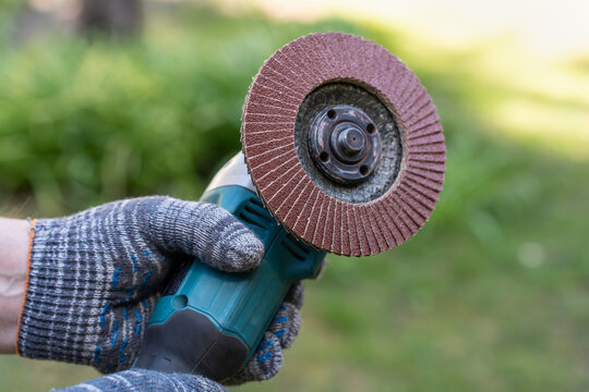 Handyman Holding Angle Grinder With Flap Disc For Grinding Wood Or Metal In Summer Garden