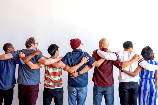 Diverse group of people standing with arms around each other.