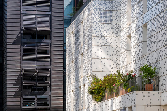 Patterned facade panels in Lyon meet trees and greenery, where plants soften glass architecture on an urban building wall in France