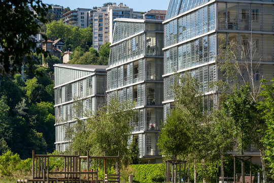 Residential glass facade blocks in Lyon sit among greenery and trees, placing plants close to urban architecture and building life in France