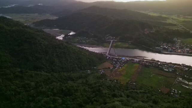 Stunning aerial view of Guinobatan in Bato, Catanduanes with river crossing, mountain terrain, and rural landscape during sunrise
