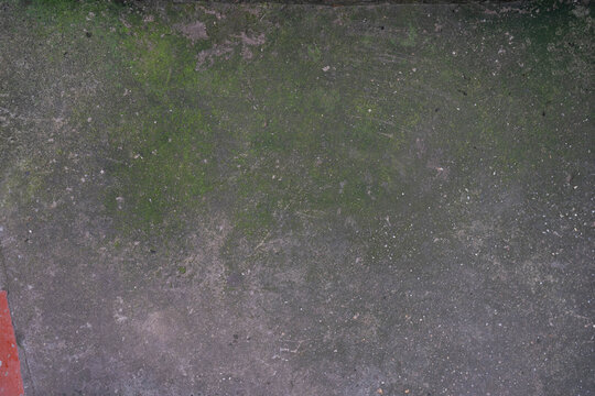 Dirty concrete surface with green moss and textured patterns.