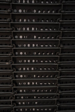 Stacked black plastic crates with a geometric design and contrasting light.