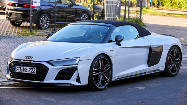 White Audi R8 Spyder V10 Performance supercar parked on a city street. Modern luxury convertible sports car with soft top roof and sleek design.