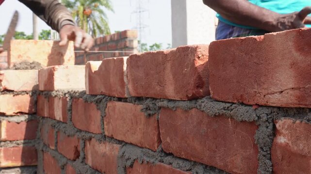 Person Constructing Brick Wall with Reddish‑Brown Bricks