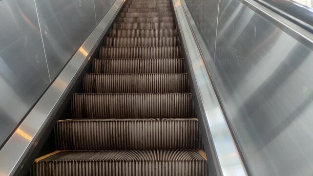 Empty metal escalator moving up in modern transport hub or shopping mall