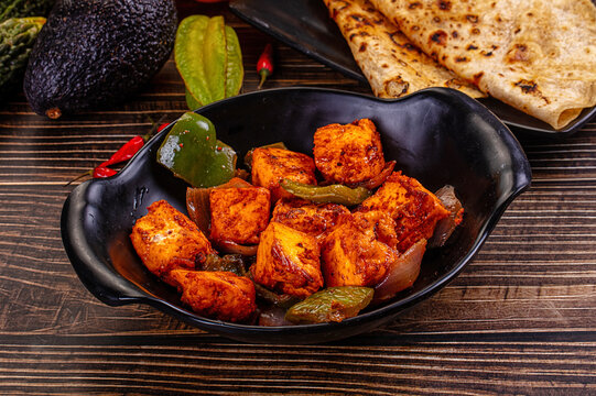 Indian Paneer Tikka Masala inl with Roti bread on a dark wooden table