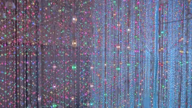 A room with mirror walls full of vertically hanging multicolor LED light stripes crates a beautiful labyrinth installation. Lumiere Light Garden in Da Lat, Vietnam
