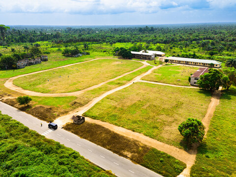 Aerial view of institutional buildings and a large grassy field surrounded by lush tropical forest in Ahoada I, Rivers, Nigeria.