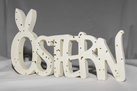 Easter decoration with wooden &ldquo;OSTERN&rdquo; lettering and bunny silhouette on soft background