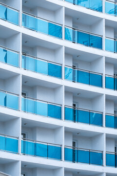 White architecture and blue balcony glass repeat across windows, where facade pattern and building exterior geometry form a clean urban grid