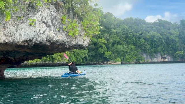 Man Kayaking Past Limestone Cliffs in the Rock Islands of Palau