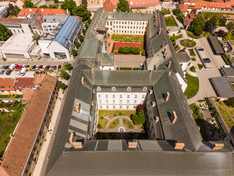 Aerial view of a large historic building with inner courtyards and green rooftops surrounded by urban streets in Trnava, Trnava Region, Slovakia.