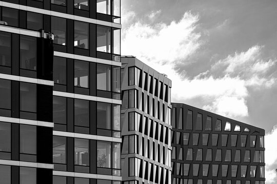 Black and white urban architecture layers building facades and cloudy sky, where windows and exterior geometry sharpen the city edge