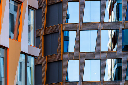 Orange facade accents cut through glass windows and dark cladding, giving urban architecture a sharp exterior geometry of color and reflection