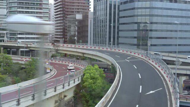 ビル群を縫うように走る首都高速道路の美しいカーブと都市風景（スローモーション）