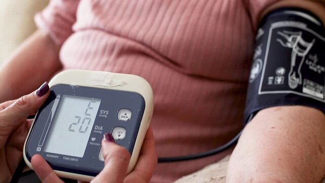 Nurse measuring blood pressure of elderly woman at home. Home healthcare visit, geriatric care, senior health monitoring, aging in place, medical assistance concept