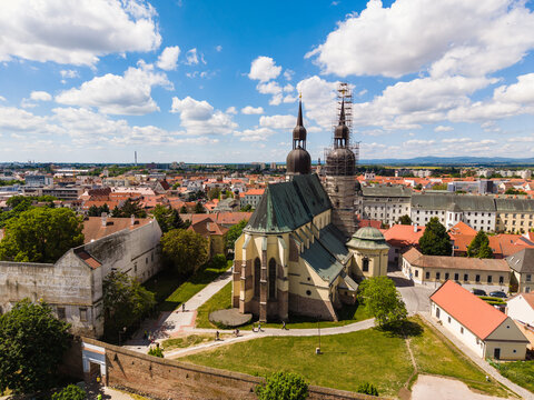 Aerial view of St. Nicholas Basilica with its twin towers and green copper roof surrounded by historic city walls and red-roofed houses in Trnava, Trnava Region, Slovakia.