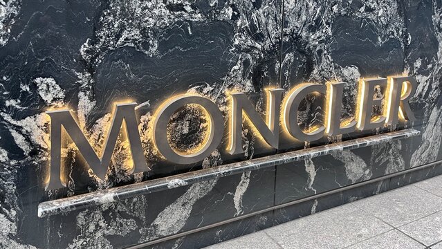 Moncler storefront logo with backlit silver lettering on luxury black marble wall at Mikimoto Ginza 2 boutique in the Chuo district - Tokyo, Japan, October 16, 2025