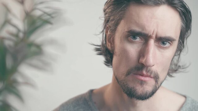 Sadness in the Eyes Beauty Close-up of a lonely mustached man dark hair beard indoors, softly lit, looking down thoughtfully gazing seriously attentively into the camera with calm, reflective mood