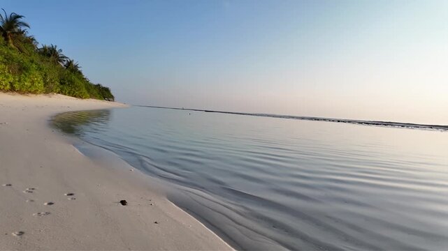 A serene video of a calm ocean with a breakwater at sunset