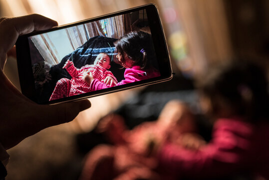 Smartphone Capturing Tender Moment Between Little Girl and Baby at Home