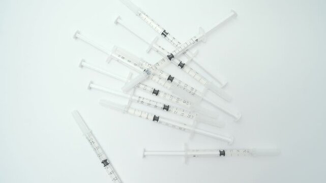 Pile of new, unused syringes falling onto an isolated white background, representing medical treatment