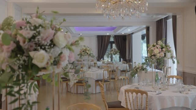Elegant banquet hall set for event with floral centerpieces and chandeliers