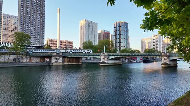 Metro train crosses Pont Rouelle above Seine, Front de Seine towers at dawn