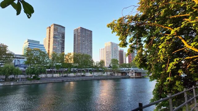 Morning shot along Quai de Grenelle with Paris metro passing beside the Seine and modern buildings.