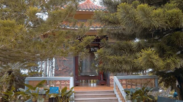 A small traditional Vietnamese Chinese pagoda with murals its walls holds a massive bronze temple bell situated in the garden of Truc Lam Zen the largest Buddhist monastery in Da Lat, Vietnam
