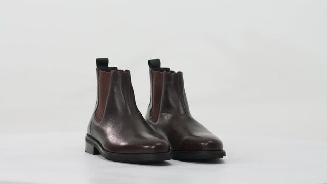 Elegant brown leather Chelsea boots rotating on a white background for a fashion product showcase