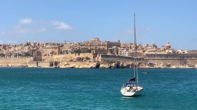 Sailboat in turquoise harbor waters of Valletta capital city of Malta.