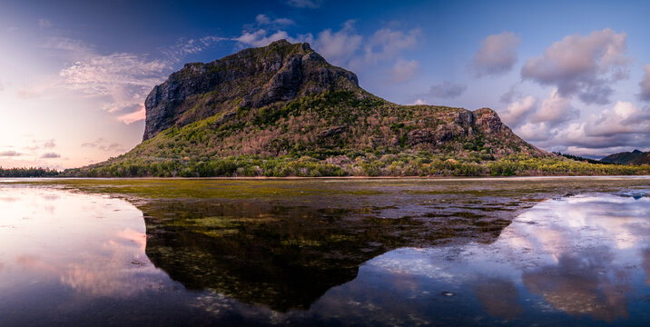 Aerial view of Le Morne Brabant mountain reflected in the calm lagoon waters during a colorful sunset in Moka District, Mauritius.