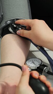 Doctor inflates cuff to check blood pressure of patient. Physician uses sphygmomanometer to obtain reliable results. Vertical video