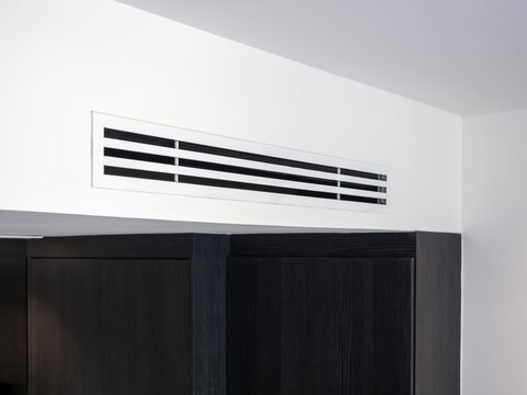 Air conditioning vent on wall ceiling in hotel room interior, featuring ventilation system, cooling airflow, and minimal design for comfort living, HVAC technology, and indoor climate control concept.